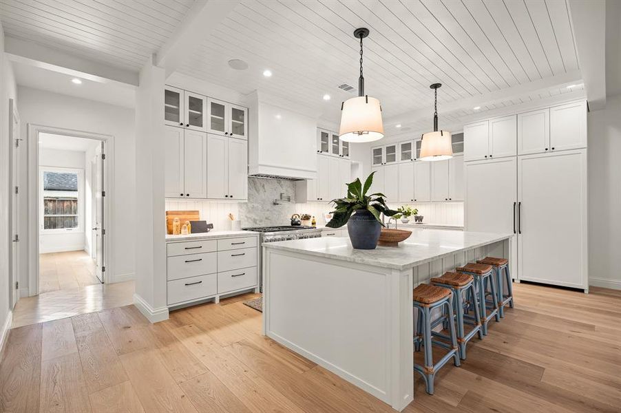 Kitchen with wooden ceiling, white cabinetry, a center island, and light hardwood / wood-style flooring