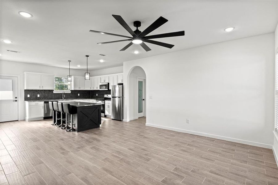Kitchen with arched walkways, a breakfast bar, dark cabinetry, hanging light fixtures, and tasteful backsplash