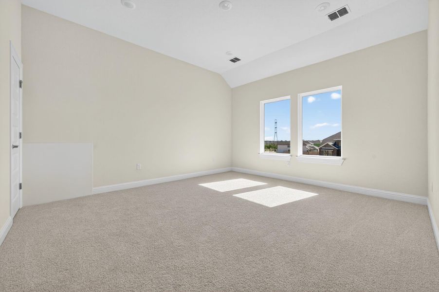 Carpeted spare room with vaulted ceiling and baseboards