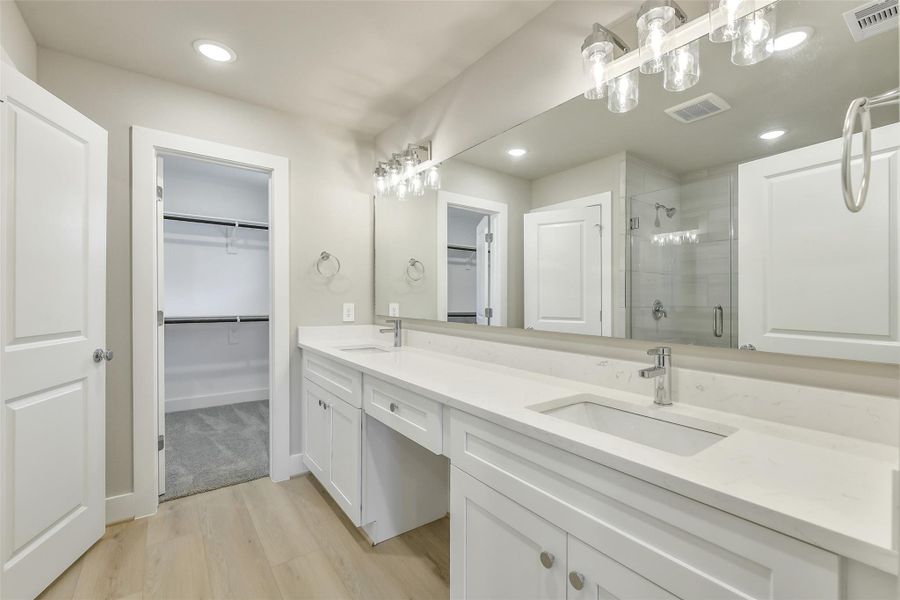 Primary bath connects directly to a spacious walk-in closet and showcases a long dual vanity with plenty of storage and counter space.