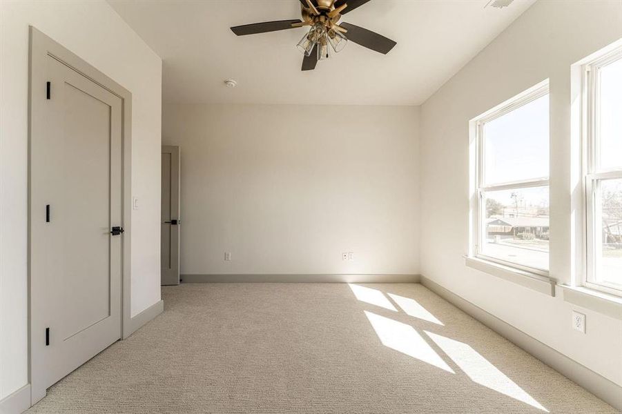Empty room with a ceiling fan and light carpet