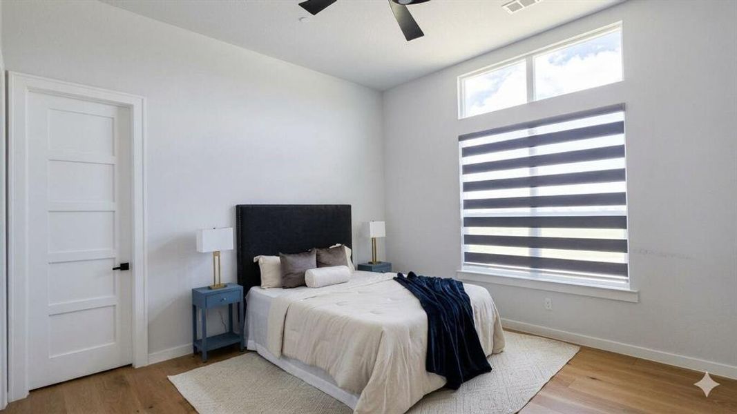 Bedroom featuring wood-finish flooring, high ceilings, a contemporary ceiling fan, and large windows with integrated blinds