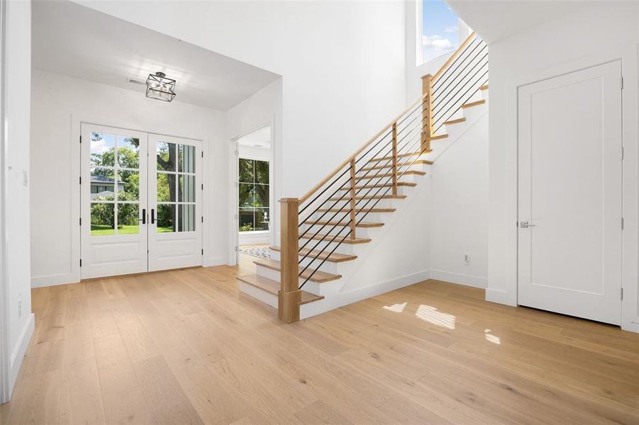 Entrance foyer featuring light wood-type flooring, french doors, and stairs Entrance foyer featuring light wood-type flooring, french doors, and stairs