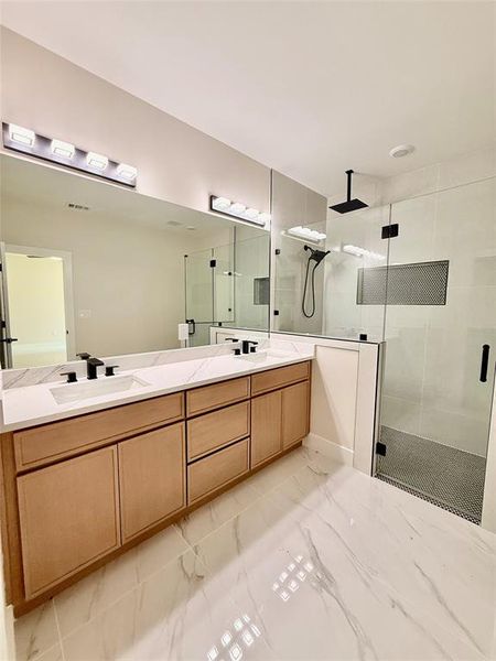 Full bathroom featuring a stall shower, double vanity, and marble look tiles