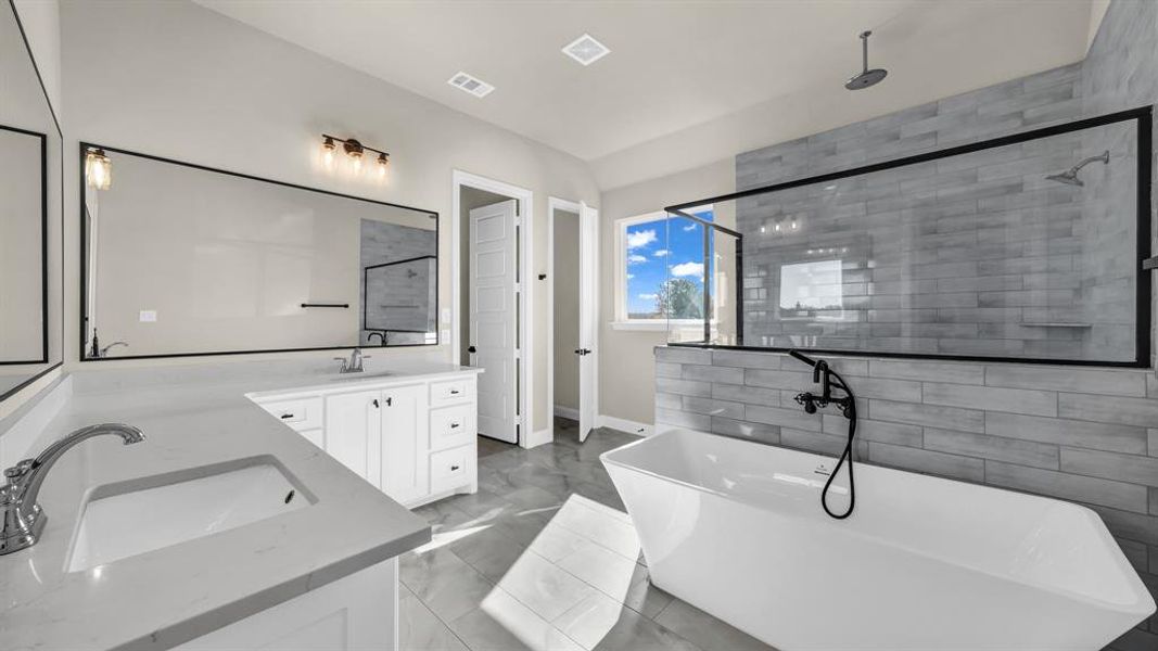 Primary bathroom features a modern, spacious design with a freestanding tub, and large walk-in shower.  Clean lines, sleek framed black accents, and neutral tones create a bright, luxurious feel.