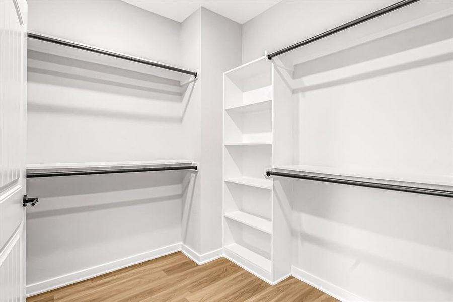 Primary closet features custom hanging rods and shelving.