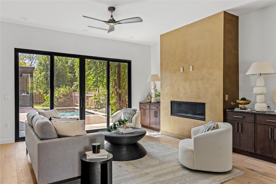 Living room featuring light wood-type flooring, a fireplace, and a ceiling fan