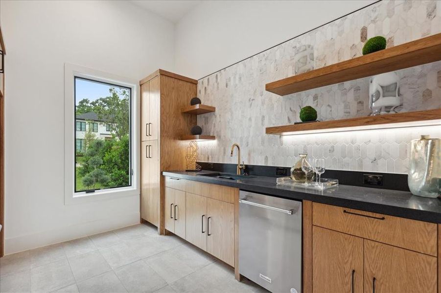 Kitchen featuring sink, dishwasher, and light tile floors