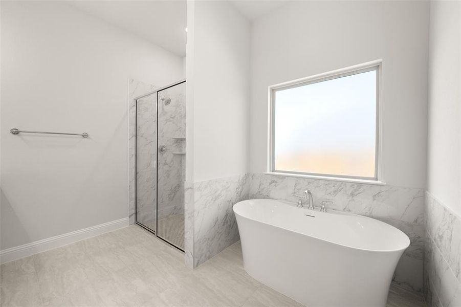 Full bathroom with a freestanding tub, a marble finish shower, tile walls, and wainscoting Full bathroom with a freestanding tub, a marble finish shower, tile walls, and wainscoting