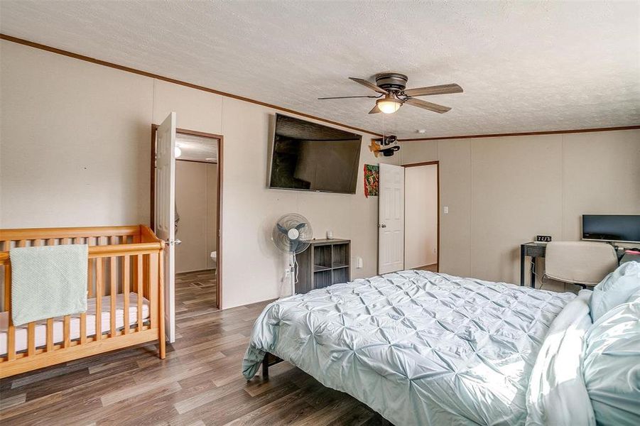 Bedroom with ceiling fan, wood-type flooring, ornamental molding, and a textured ceiling