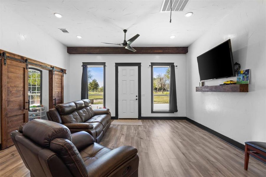 Living room with plenty of natural light, a barn door, wood finished floors, attic access, and recessed lighting Living room with plenty of natural light, a barn door, wood finished floors, attic access, and recessed lighting