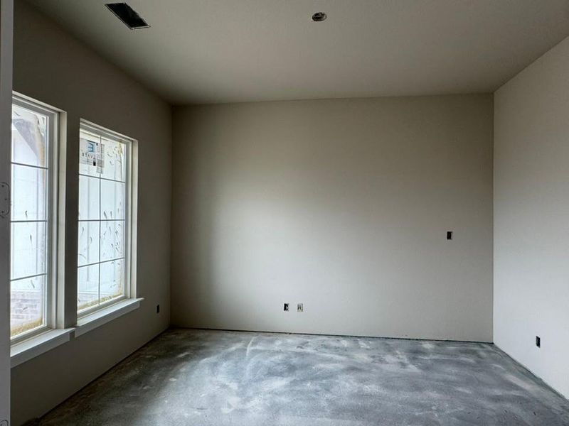 Unfinished interior room featuring two large windows with mullions and a concrete subfloor