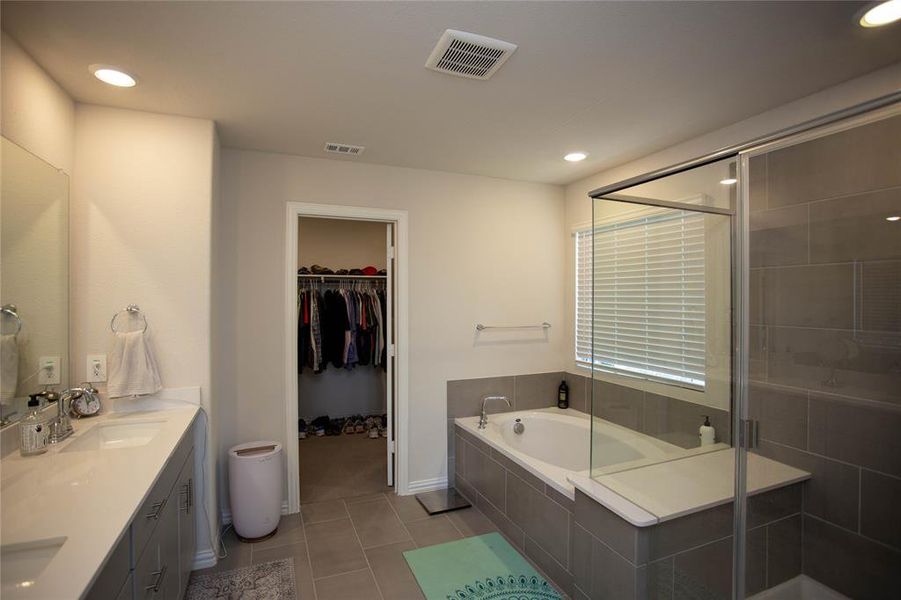 Full bath featuring a sink, visible vents, a garden tub, and a shower stall
