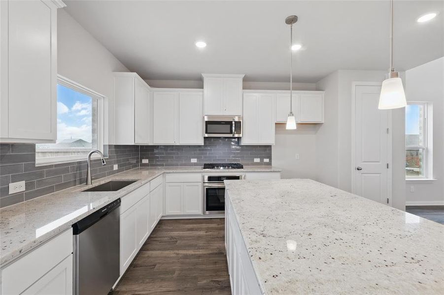 Kitchen with appliances with stainless steel finishes, light stone counters, white cabinets, and recessed lighting