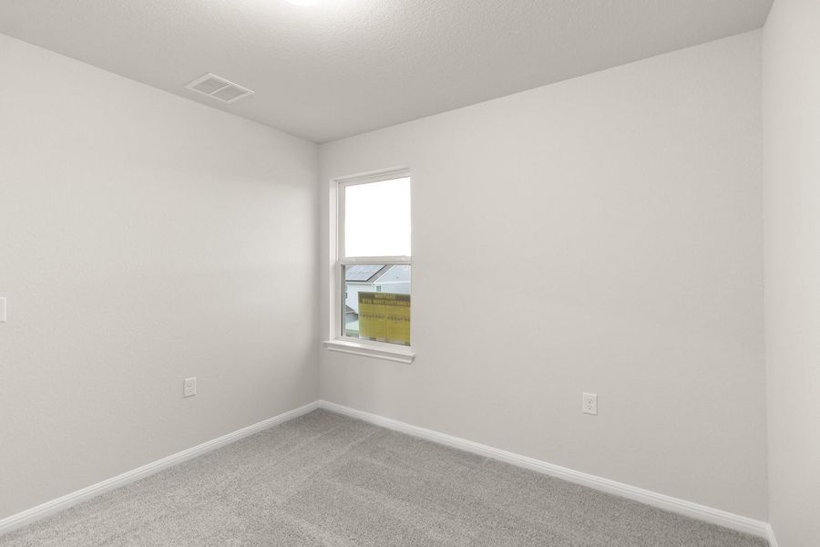 This room features plush grey carpeting, light-colored walls, and a window providing natural illumination