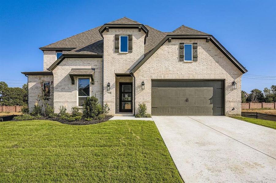 French country home featuring brick siding, a shingled roof, concrete driveway, a front yard, and a garage French country home featuring brick siding, a shingled roof, concrete driveway, a front yard, and a garage