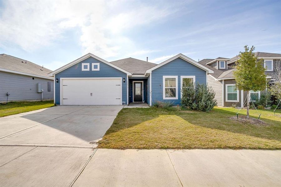 Single story home with driveway, a front yard, and an attached garage