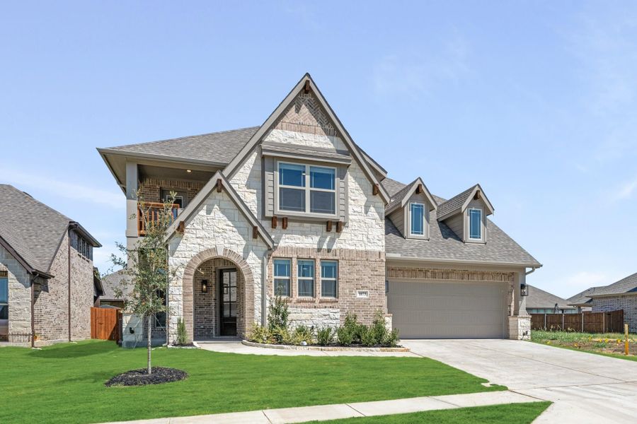 Two-story home with stone and brick exterior, arched entry, second-floor balcony, and two-car garage Two-story home with stone and brick exterior, arched entry, second-floor balcony, and two-car garage
