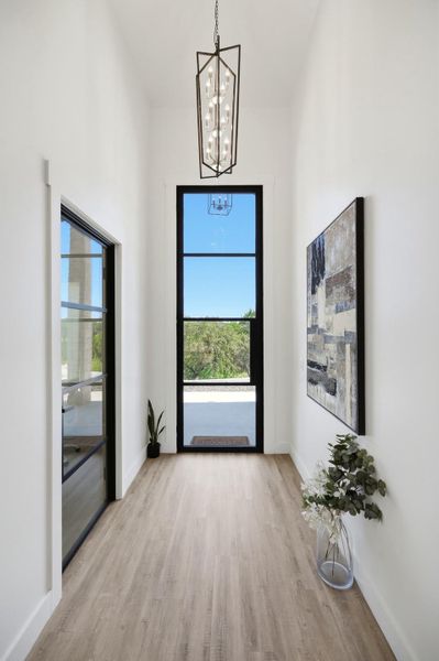 Towering ceilings and light wood floors frame a dramatic glass entryway overlooking the garden.