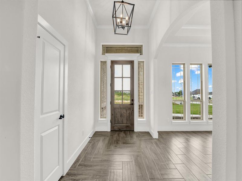 Foyer entrance with arched walkways, ornamental molding, and a chandelier