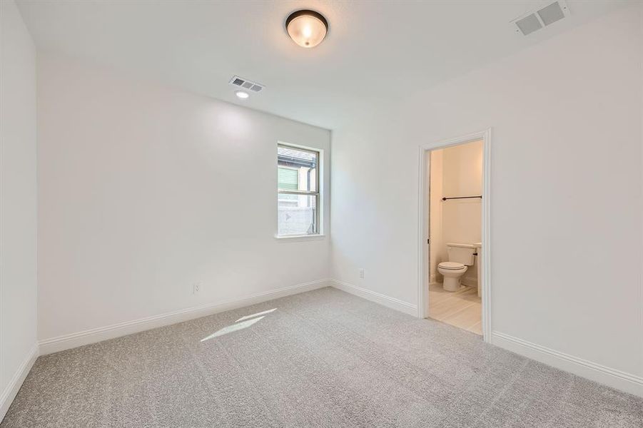 Unfurnished bedroom with light colored carpet and ensuite bathroom