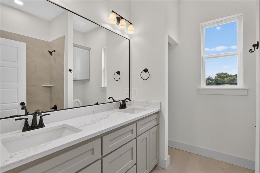 Double vanity with integrated rectangular sinks, white stone countertop with veining, and matte black fixtures Double vanity with integrated rectangular sinks, white stone countertop with veining, and matte black fixtures