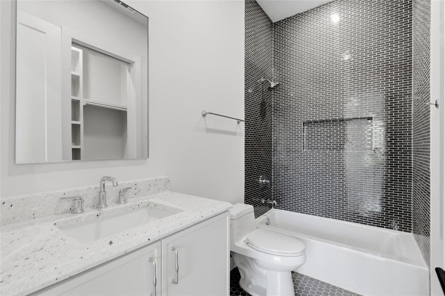 Secondary bath with granite countertop vanity, glass-enclosed shower, and mosaic tile surround Secondary bath with granite countertop vanity, glass-enclosed shower, and mosaic tile surround