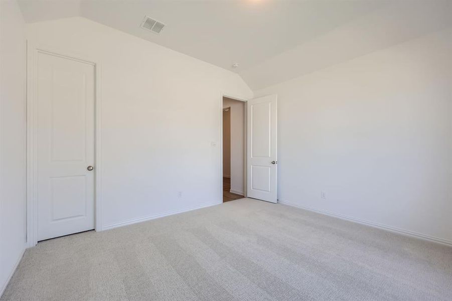 Unfurnished room with vaulted ceiling and light carpet