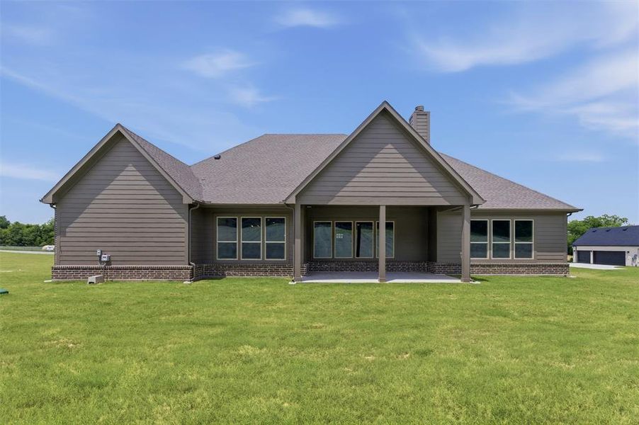 Rear exterior featuring horizontal siding, a covered patio, multiple large windows, and a stone veneer foundation