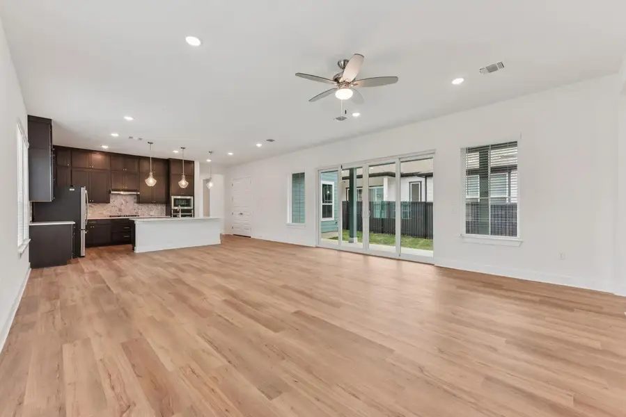Open-concept living area featuring wood-finish flooring, recessed lighting, and a ceiling fan