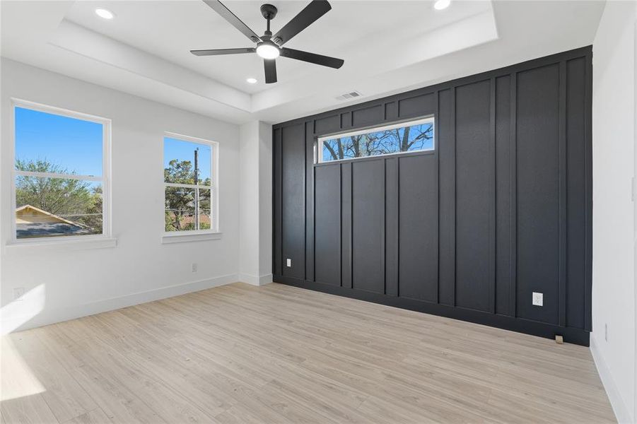 Empty room with ceiling fan, recessed lighting, light wood-type flooring, and a tray ceiling Empty room with ceiling fan, recessed lighting, light wood-type flooring, and a tray ceiling