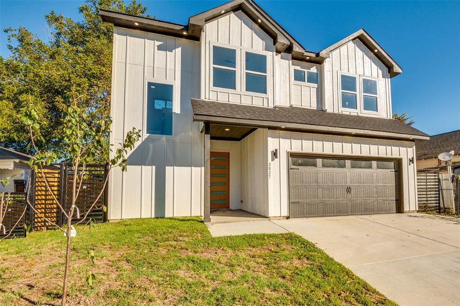 View of front of house featuring board and batten siding, a garage, concrete driveway, and roof with shingles