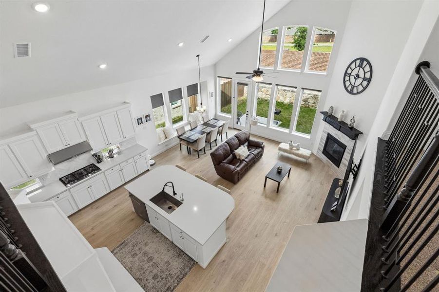Open-concept living space featuring a vaulted ceiling, wood-finish flooring, and white cabinetry