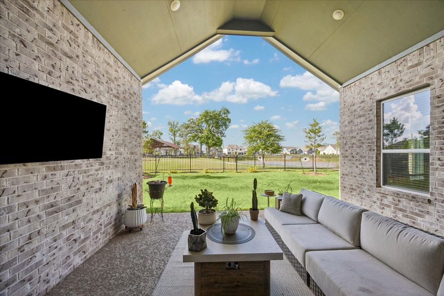 Covered outdoor living area framed by brick and a vaulted ceiling, offering a comfortable extension of the interior space. Uninterrupted views across the backyard to the water and greenbelt create a peaceful, open backdrop. Covered outdoor living area framed by brick and a vaulted ceiling, offering a comfortable extension of the interior space. Uninterrupted views across the backyard to the water and greenbelt create a peaceful, open backdrop.