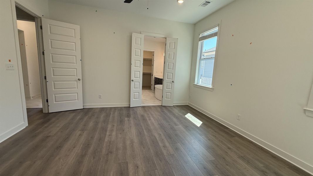 Unfurnished bedroom with dark wood finished floors, connected bathroom, and a ceiling fan