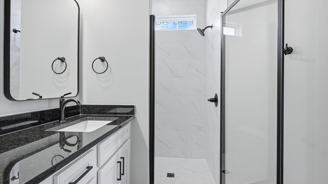 Tasteful primary bath with modern finishes, a tiled walk-in shower, and thoughtful double vanity layout