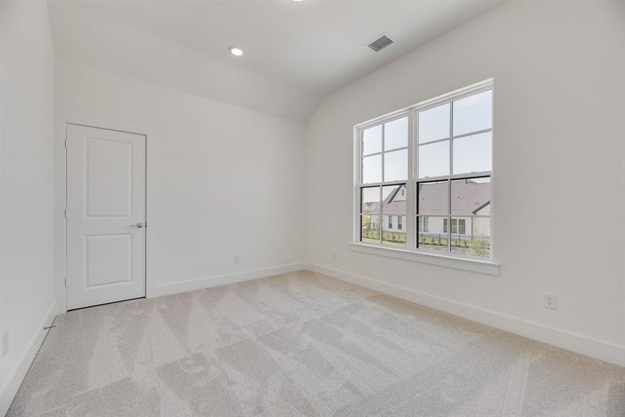 Unfurnished room featuring light colored carpet, vaulted ceiling, recessed lighting, and a residential view