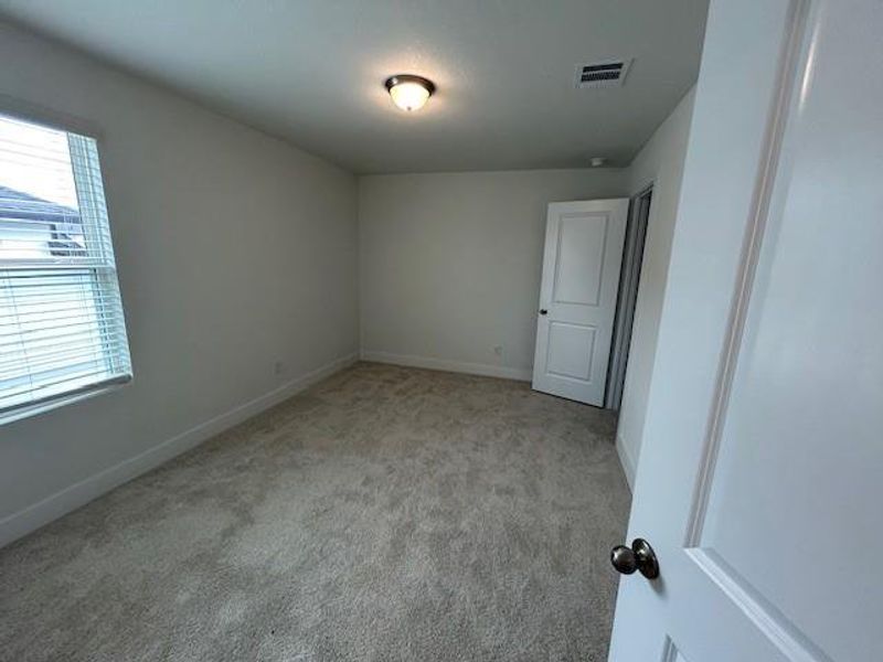 Carpeted spare room featuring visible vents and baseboards