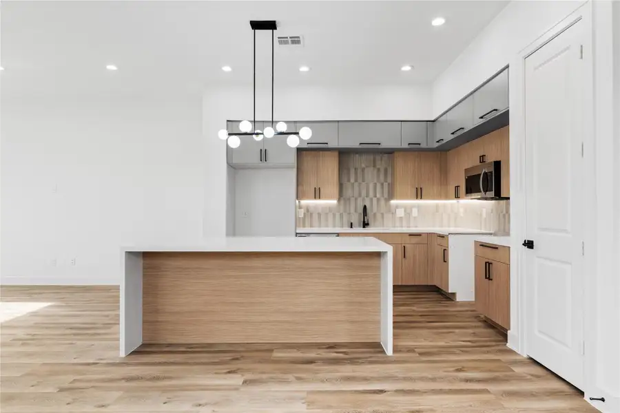 A second view of the kitchen highlights the generous island and clean, modern finishes that elevate the space. With plenty of room to cook, gather, and host, this kitchen is designed to impress.