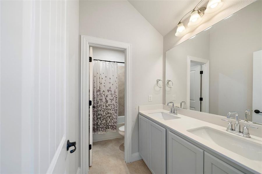 Full bathroom featuring tile patterned flooring, shower / bath combo, toilet, lofted ceiling, and vanity