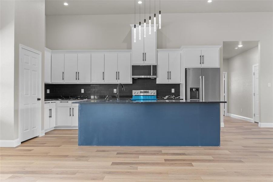 Kitchen with white cabinets, appliances with stainless steel finishes, recessed lighting, decorative backsplash, and light wood-style flooring