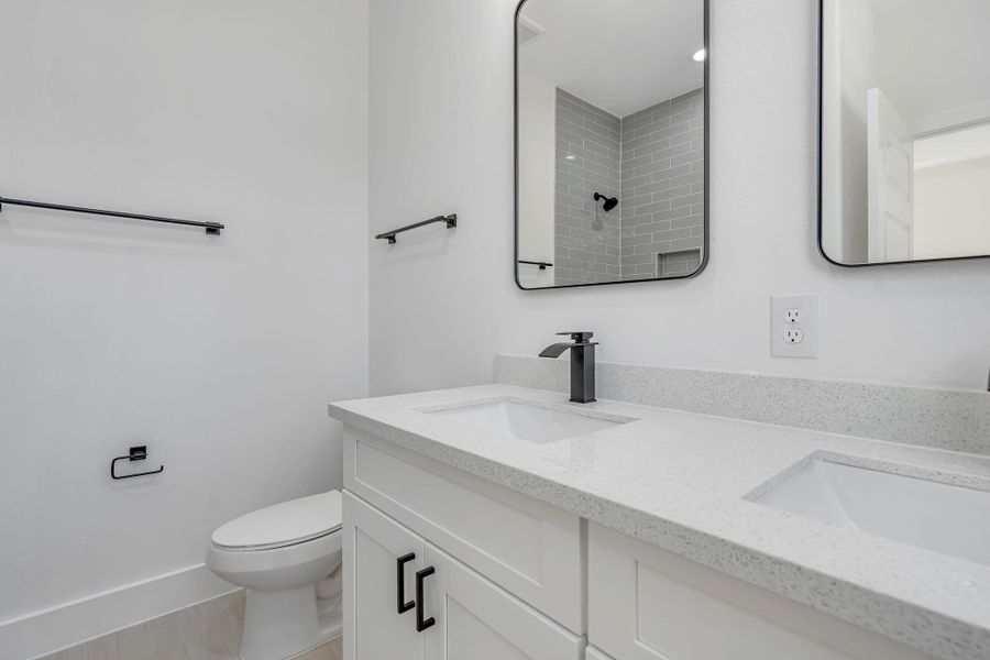 Primary bathroom featuring a double-sink quartz vanity, modern black fixtures, and clean contemporary finishes.