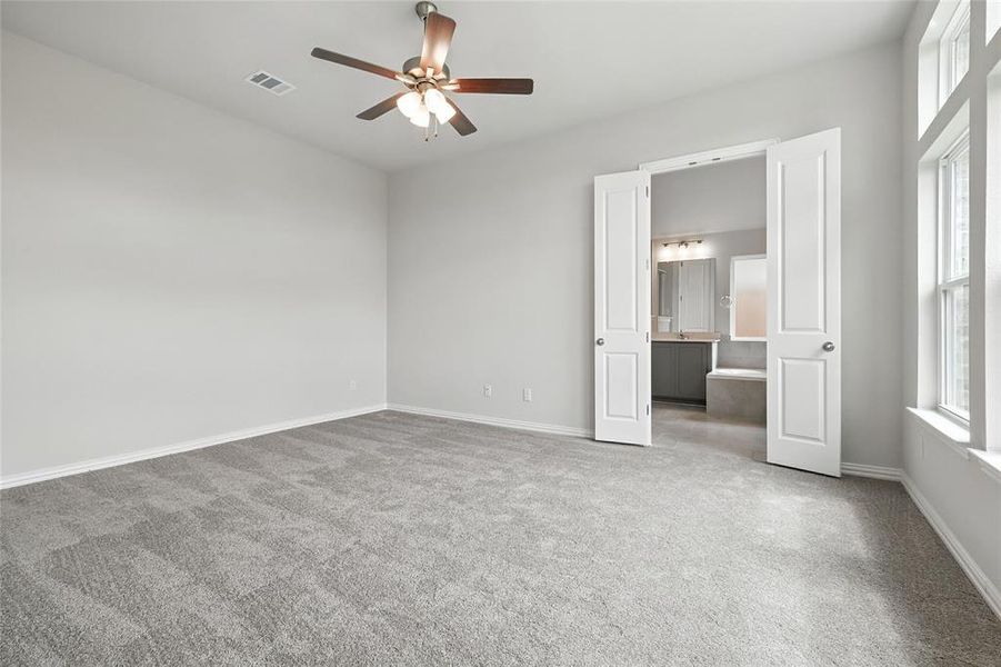 Unfurnished bedroom with light colored carpet, ceiling fan, and ensuite bathroom