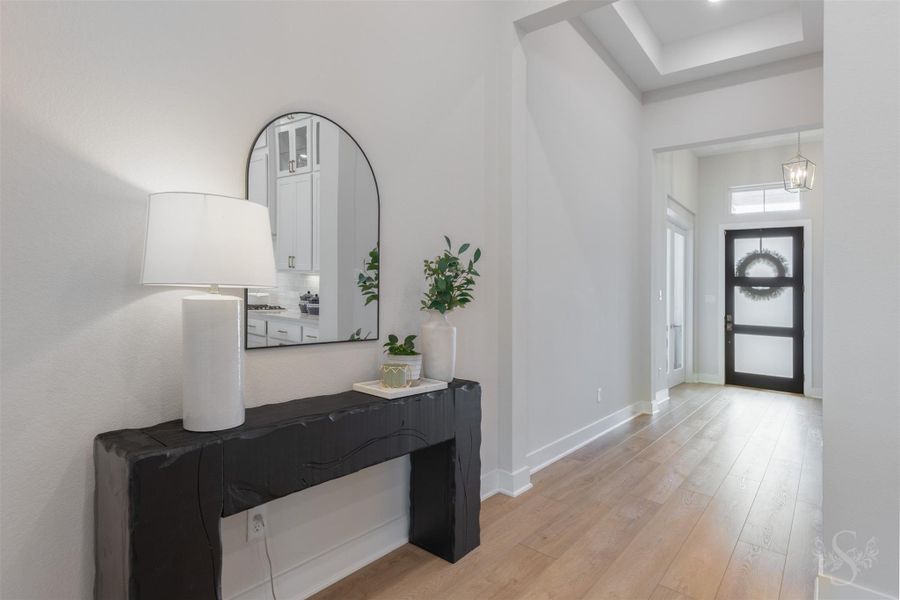 The impressive entry sets the tone with gorgeous vinyl plank flooring, a sleek modern front door and striking tray ceiling details. Contemporary lighting adds the perfect touch to this beautifully designed space. The impressive entry sets the tone with gorgeous vinyl plank flooring, a sleek modern front door and striking tray ceiling details. Contemporary lighting adds the perfect touch to this beautifully designed space.