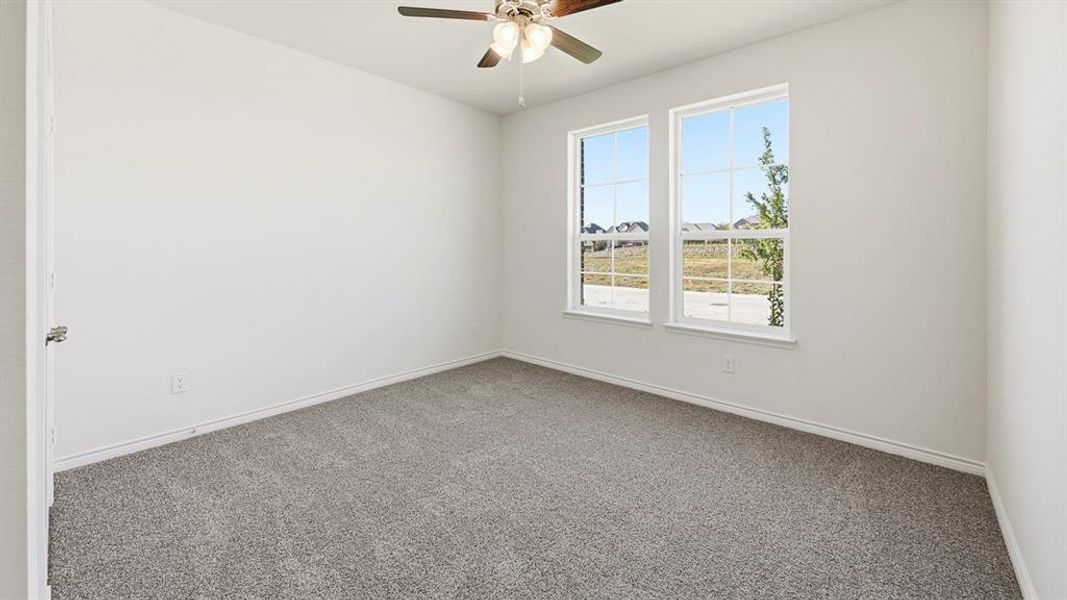 Carpeted empty room featuring baseboards and ceiling fan