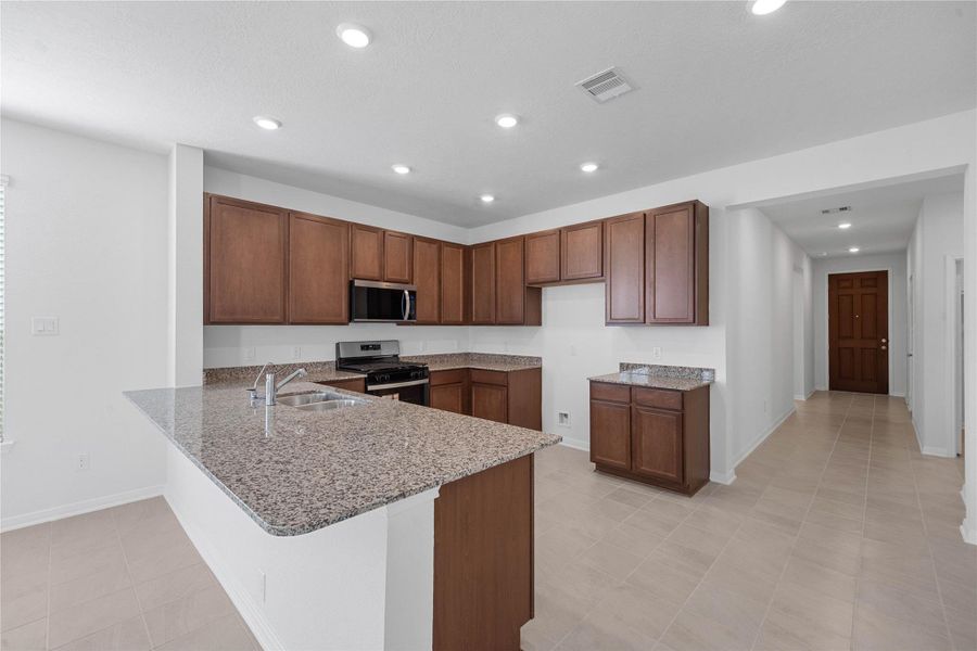 The kitchen exudes warmth with stunning Caramel Cream granite countertops perfectly paired with the rich, inviting tone of the Woodmont cabinetry in a Ginger stain. This combination creates a truly gorgeous and cohesive aesthetic.