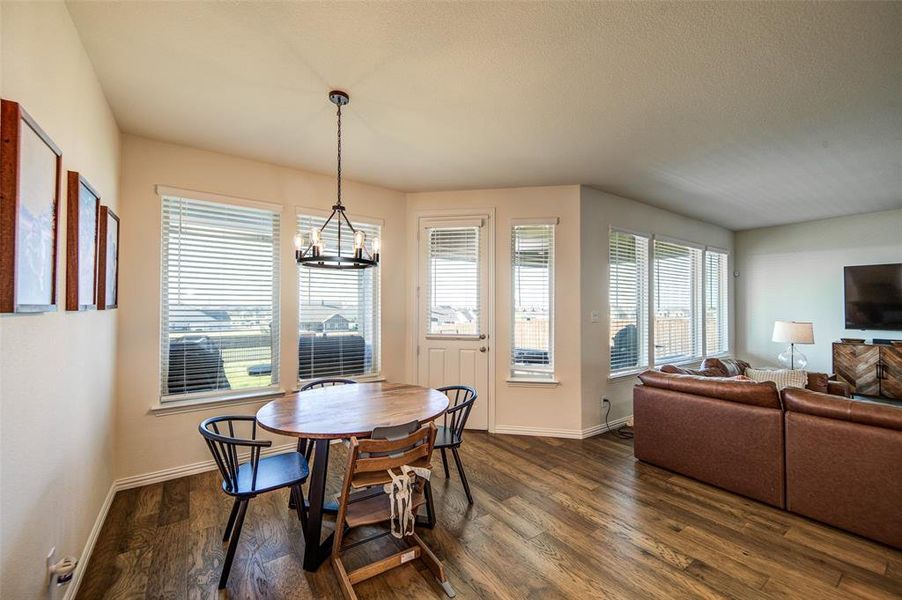 Dining area featuring dark wood-style flooring, plenty of natural light, a chandelier, and a textured ceiling