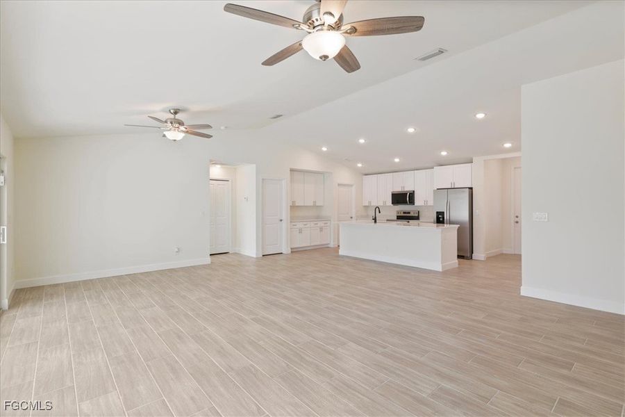 Unfurnished living room with vaulted ceiling, wood finish floors, a ceiling fan, and recessed lighting