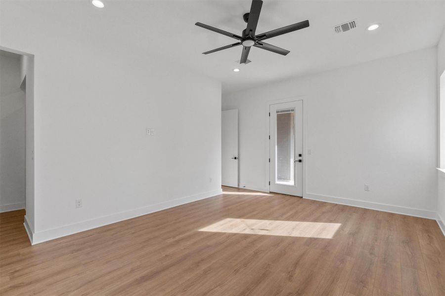 Well-lit living area featuring rich wood flooring, a modern ceiling fan, and access to the outdoors. Well-lit living area featuring rich wood flooring, a modern ceiling fan, and access to the outdoors.
