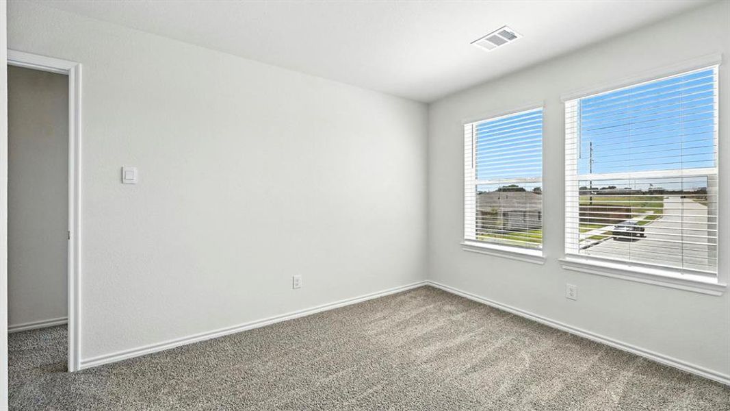 Bright interior room with two windows, textured light gray walls, white trim, and gray speckled carpeting